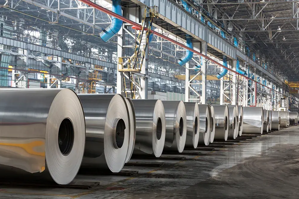 Large metal coils lined up inside a production facility.