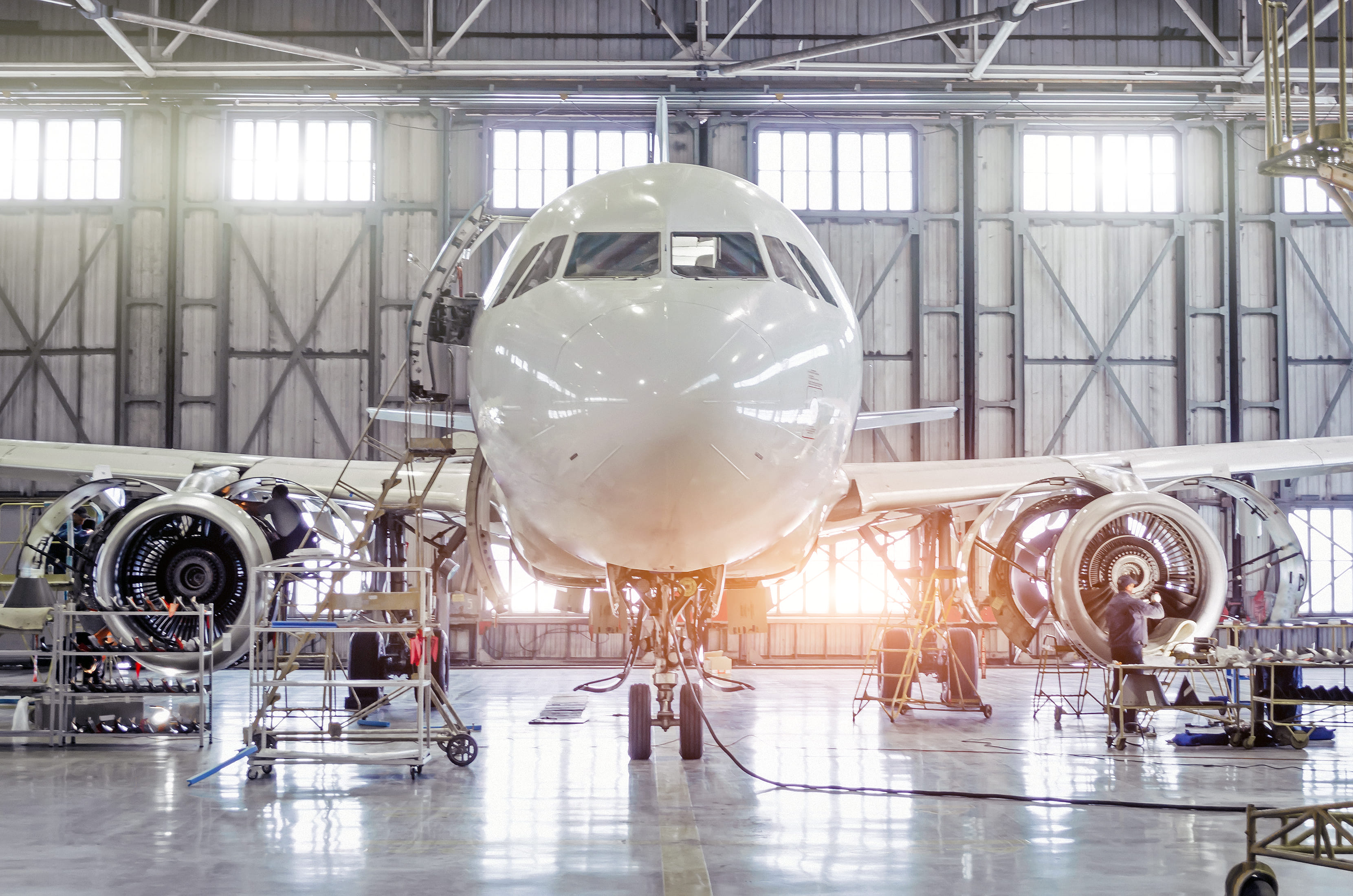 Aircraft undergoing maintenance inside an aerospace hangar.