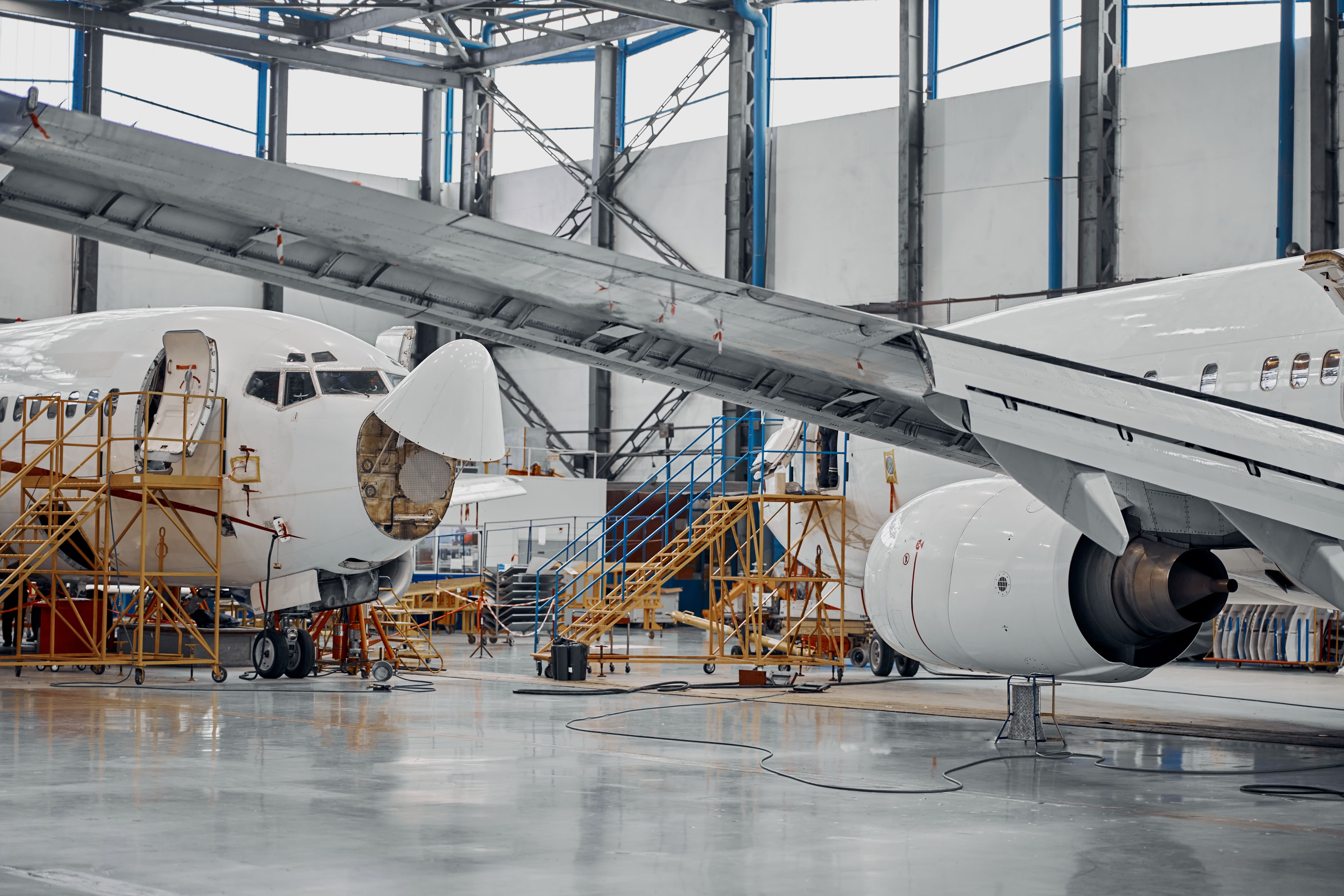 Aircraft undergoing maintenance inside an aerospace hangar.