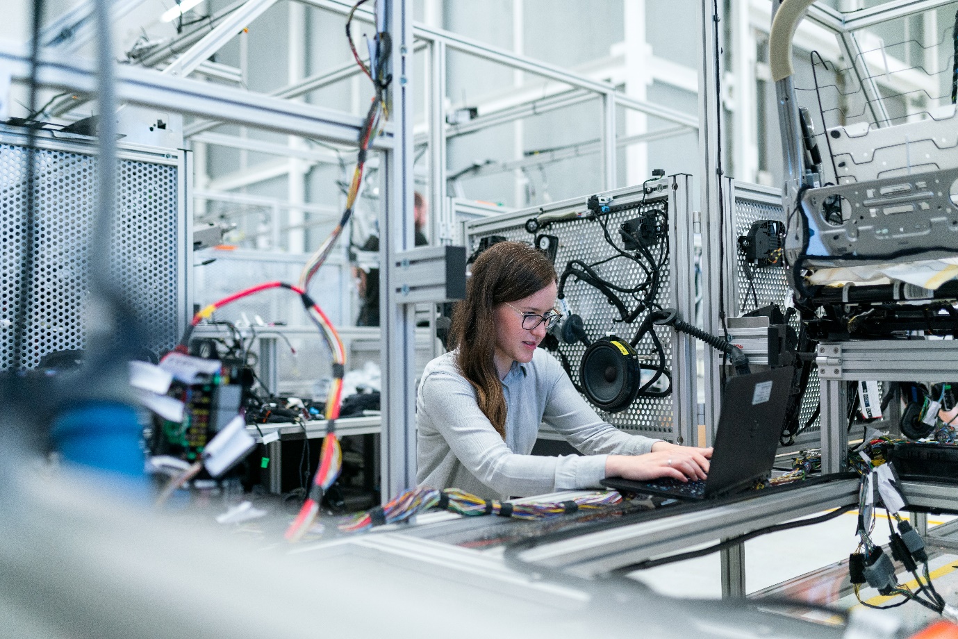 Engineer reviewing controlled production information on a tablet beside industrial equipment.